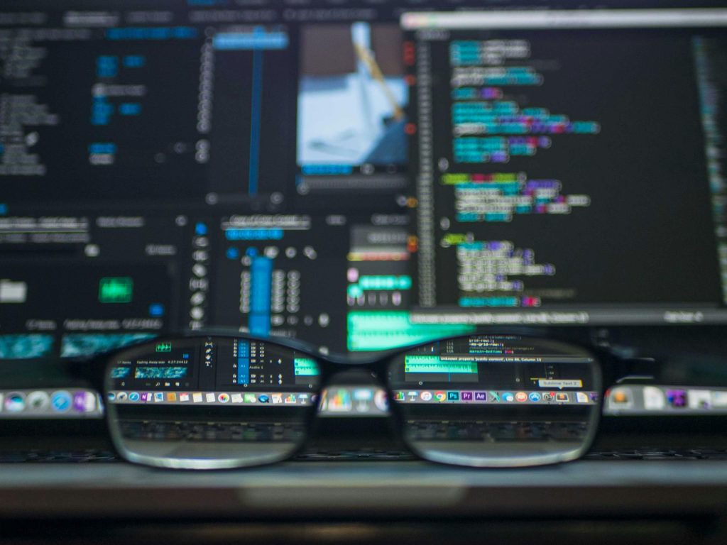 SaaS Platforms for B2B & B2C Eyeglasses reflecting computer code on a monitor, ideal for technology and programming themes.
