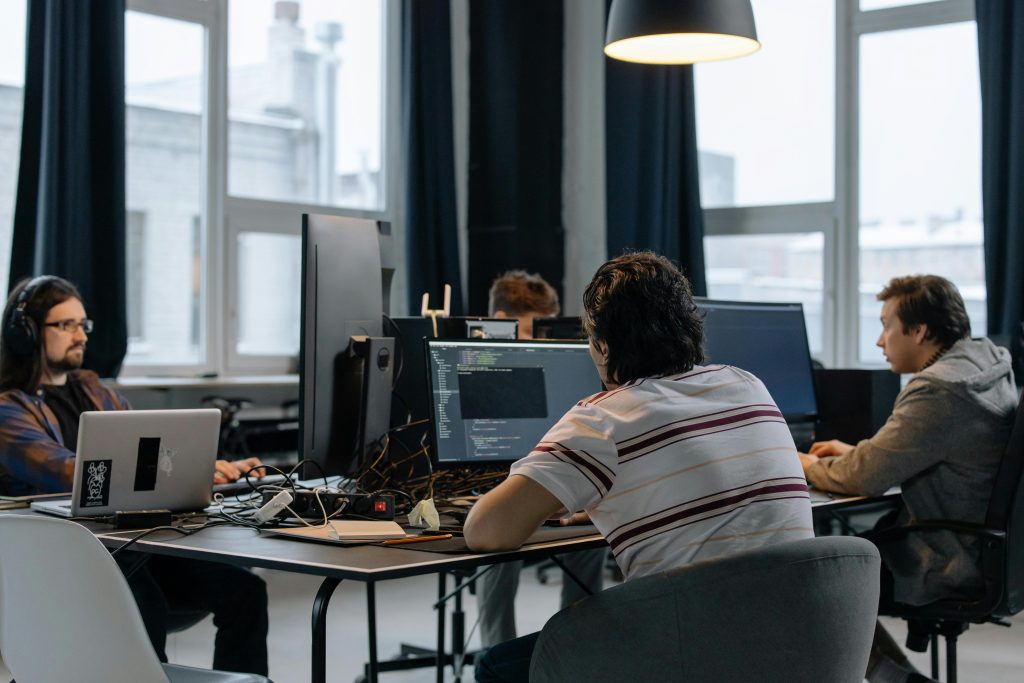Who We Are Team of developers working together on computers in a modern tech office.