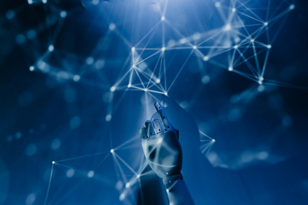 Innovative Technology A robotic hand reaching into a digital network on a blue background, symbolizing AI technology.